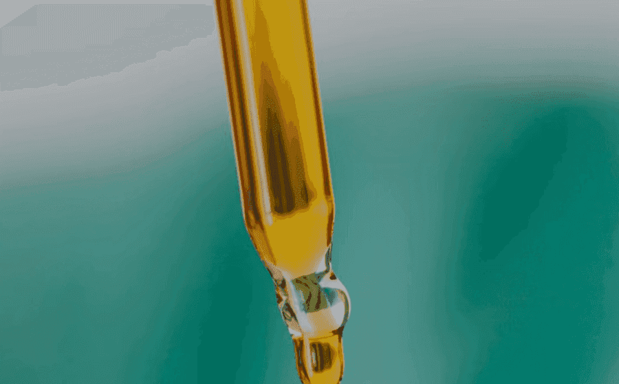 Amber dropper releasing a single drop of herbal oil.